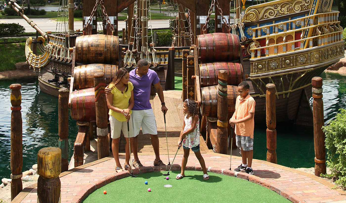 family of four in front of pirate ship waiting to putt